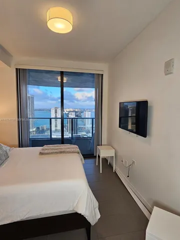 a living room with a bed furniture and a flat tv screen next to a window