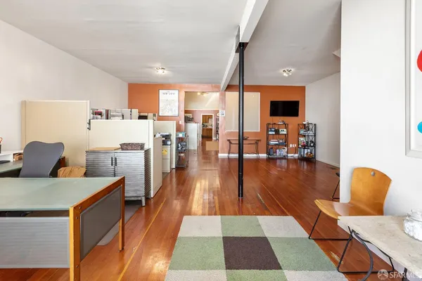 a living room with stainless steel appliances furniture wooden floor and a view of kitchen