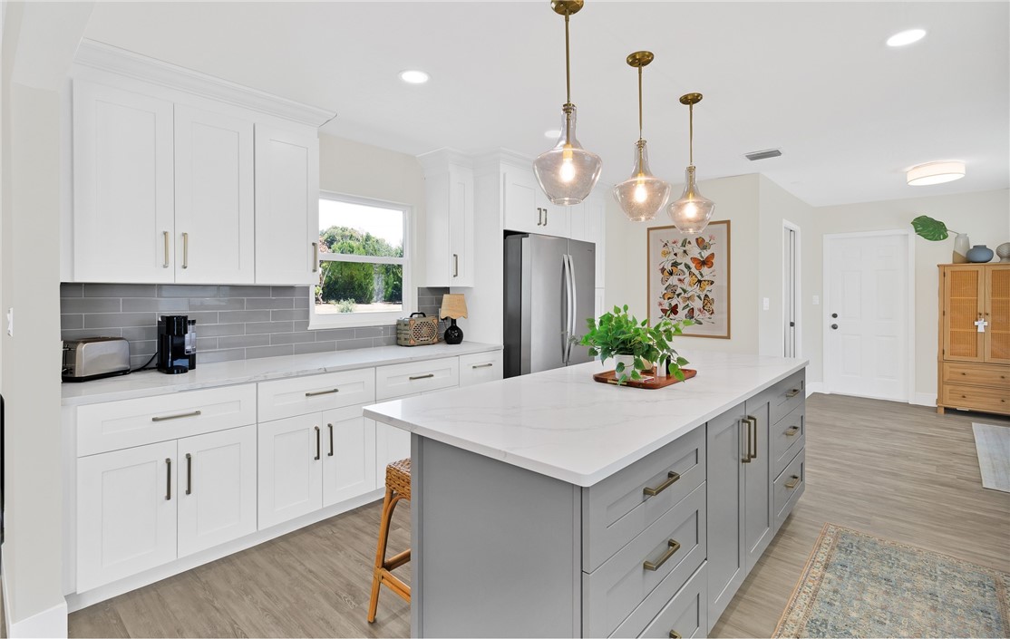 7989 143rd Street Sebastian, FL 32958 - Photo 9 of 30 a kitchen with white cabinets and center island