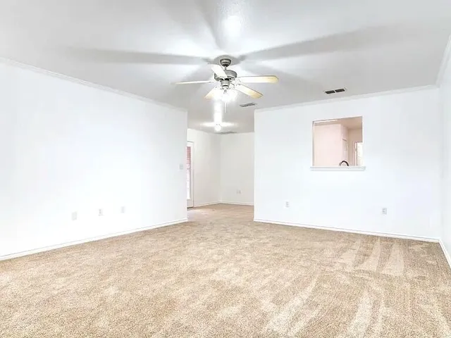 an empty room with a chandelier fan and wooden floor