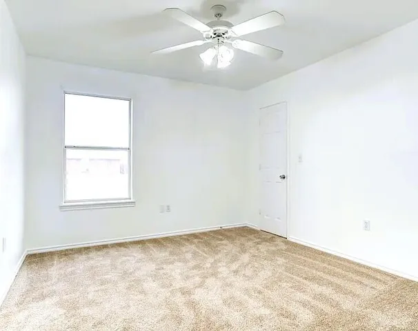 an empty room with a window and a fan