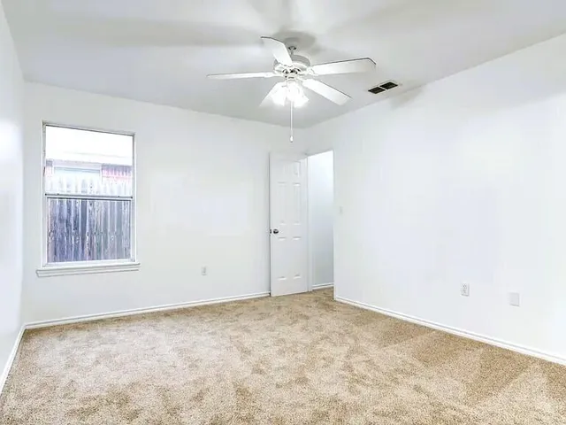 an empty room with windows and fan