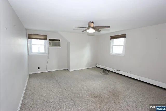 an empty room with windows and ceiling fan
