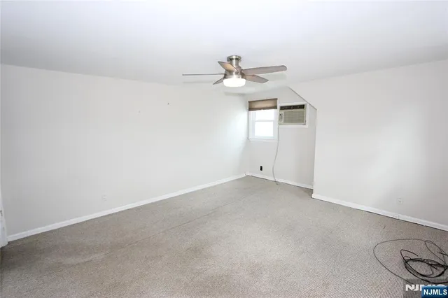 an empty room with a ceiling fan and window