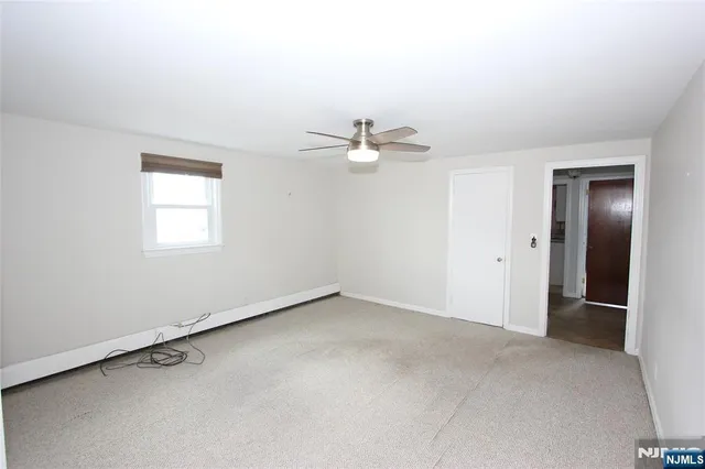 an empty room with a window and a ceiling fan