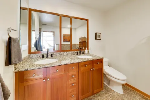 a bathroom with a granite countertop sink toilet and mirror