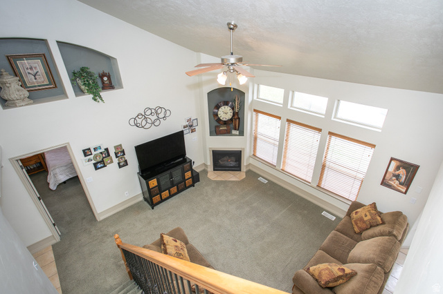 426 Deer Hollow Road Tooele, UT 84074 - Photo 10 of 37 Living area featuring high vaulted ceiling, a fireplace with flush hearth, light colored carpet, a ceiling fan, and a textured ceiling