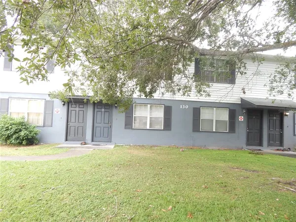 a front view of house with yard and trees in the background