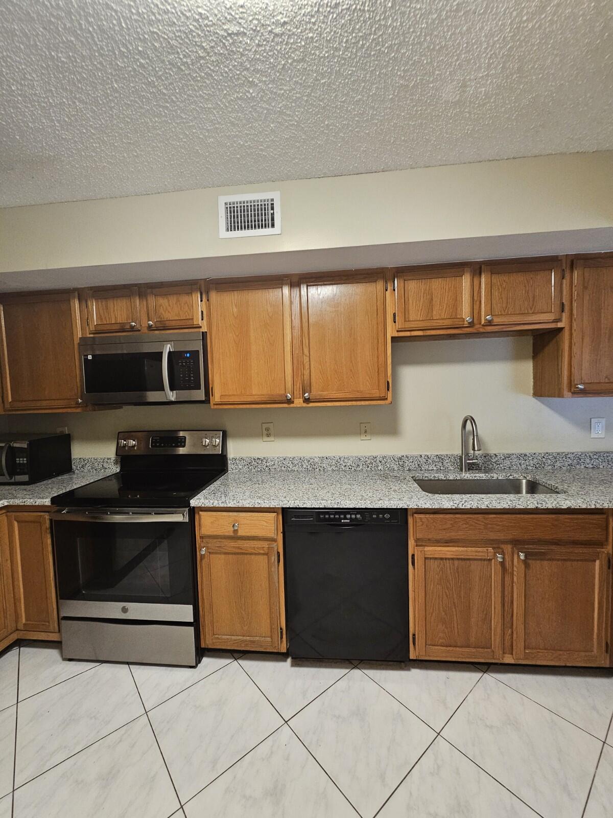 3150 Leewood Terrace, Unit L222 Boca Raton, FL 33431 - Photo 9 of 39 a kitchen with stainless steel appliances granite countertop a stove a sink and a microwave