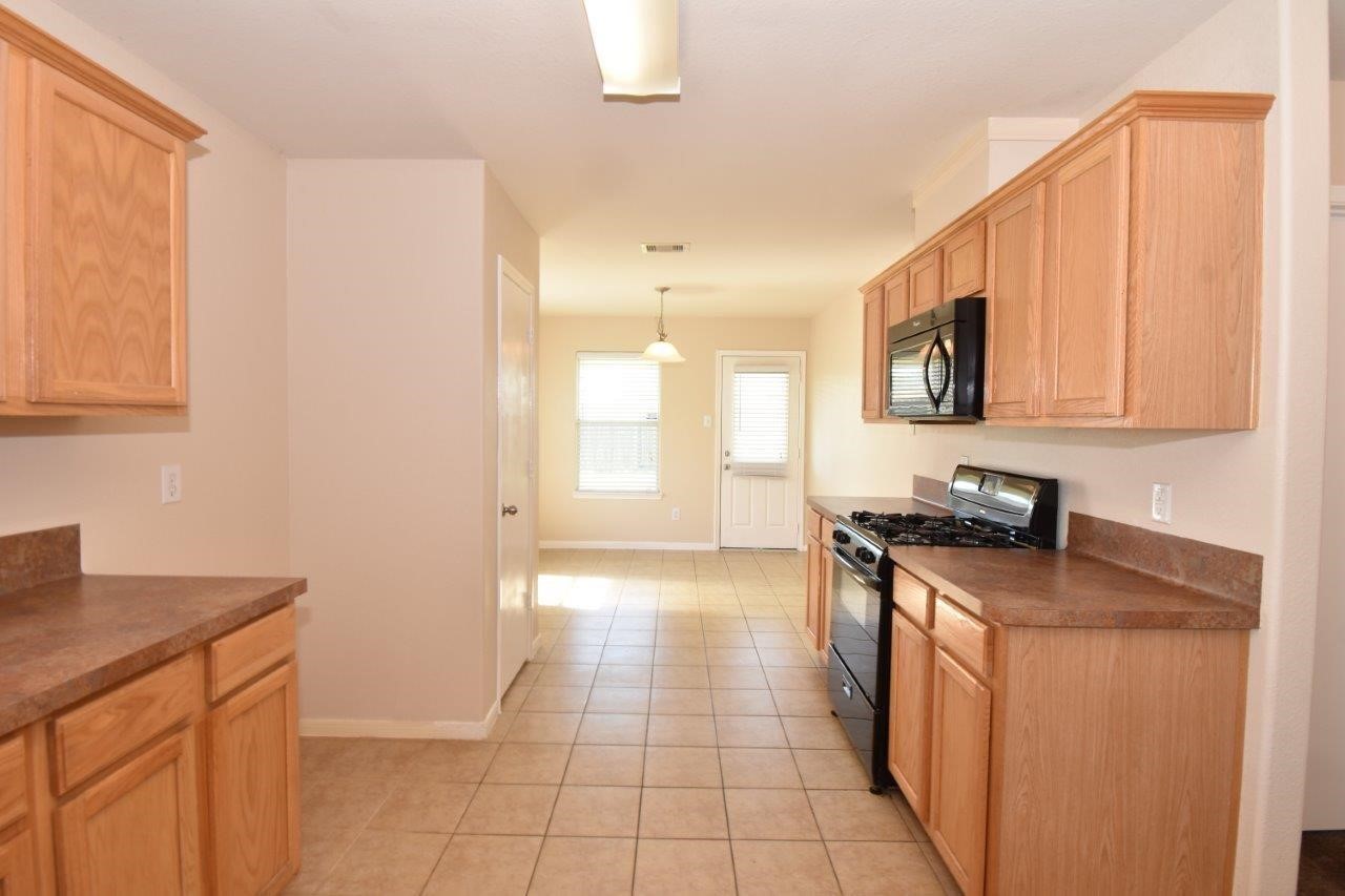 1126 Desert Oasis Lane Rosenberg, TX 77471 - Photo 6 of 16 a kitchen with stainless steel appliances granite countertop a stove a sink and a microwave