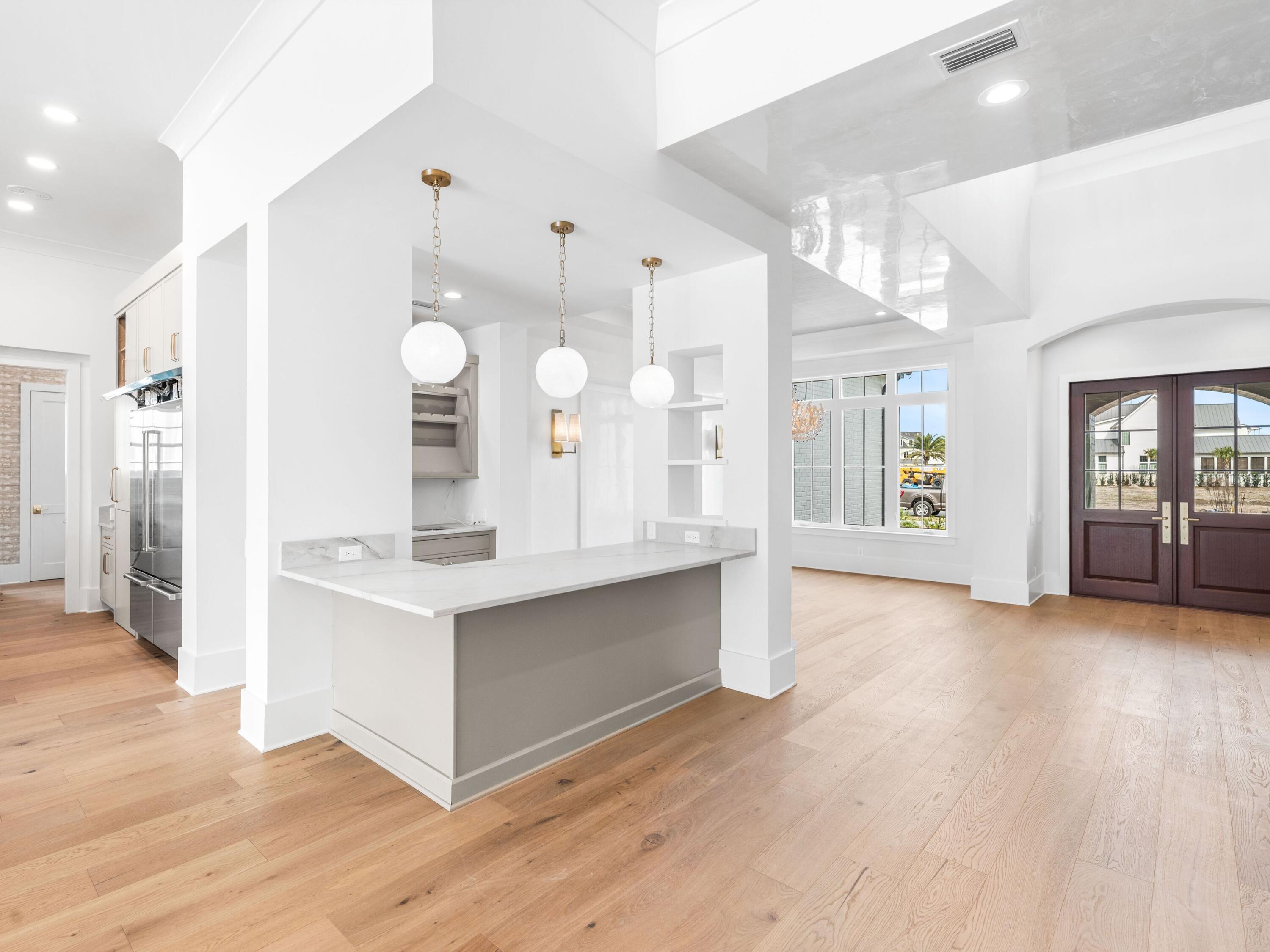 303 Golfridge Drive Watersound, FL 32461 - Photo 16 of 50 a large white kitchen with a refrigerator a sink dishwasher and a fireplace with wooden floor