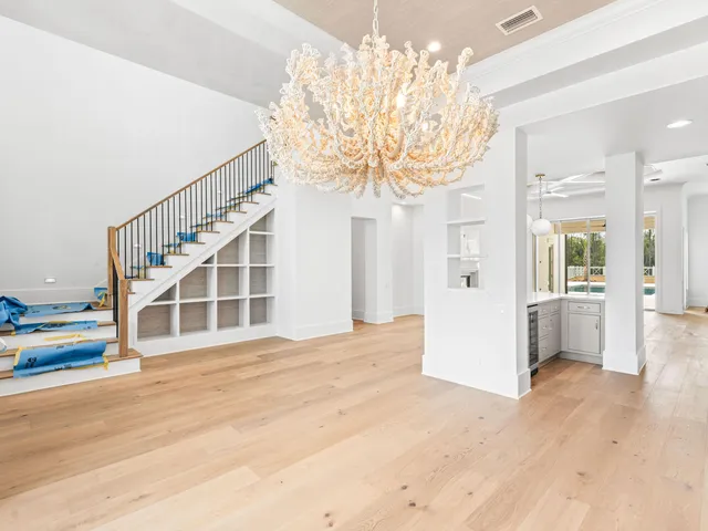a view of a hallway with wooden floor and chandelier