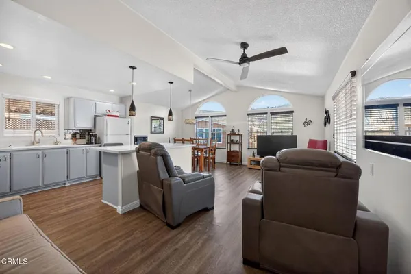 a living room with furniture kitchen view and a wooden floor