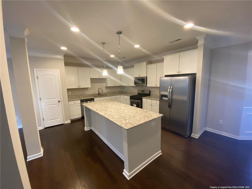 1206 Wingstem Place Raleigh, NC 27607 - Photo 11 of 17 a kitchen with stainless steel appliances kitchen island granite countertop a refrigerator a sink dishwasher a stove and a oven with wooden floor