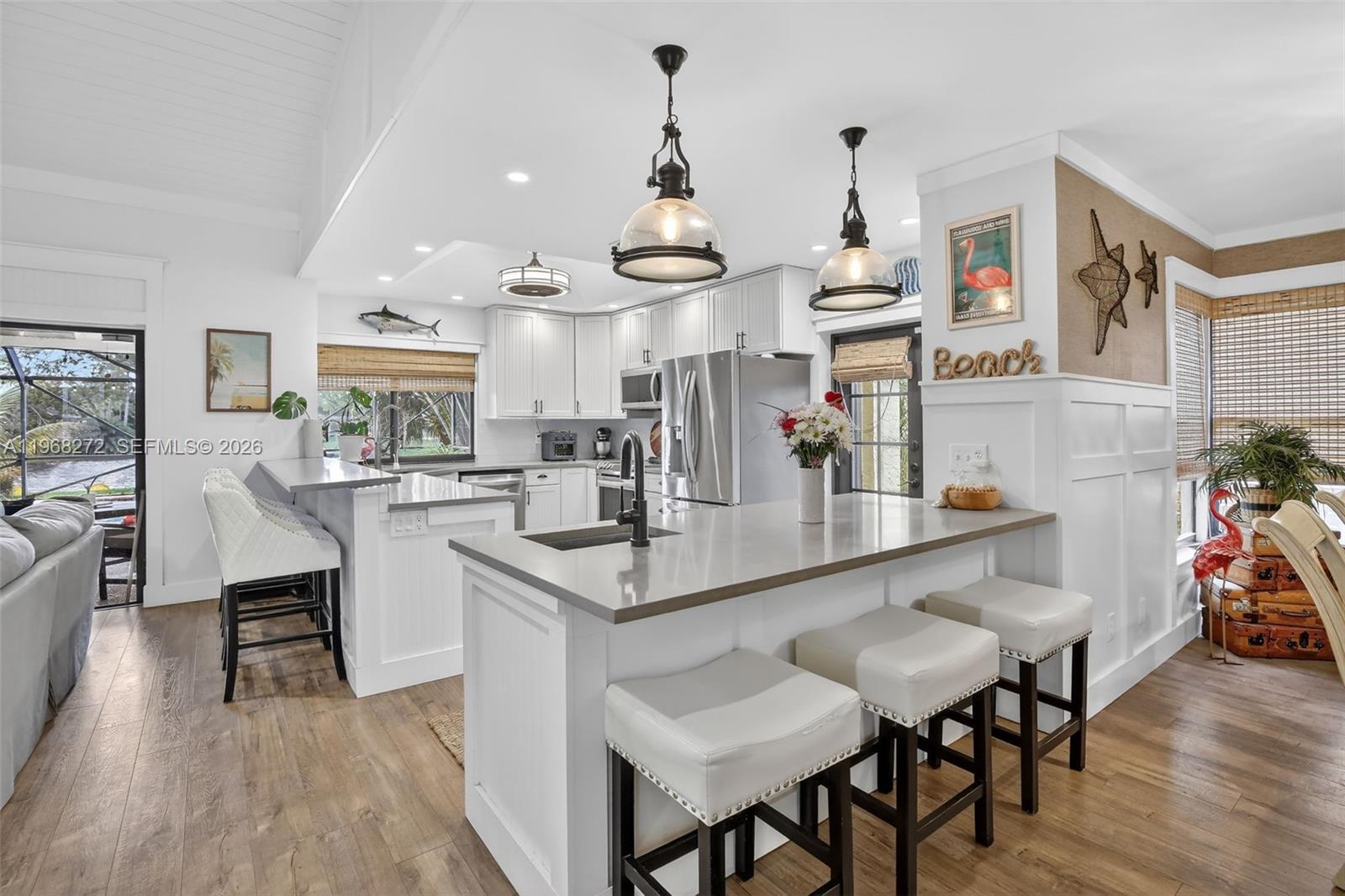 8740 Southwest 56th Place Cooper City, FL 33328 - Photo 15 of 54 a kitchen with stainless steel appliances kitchen island granite countertop a table chairs in it and wooden floors