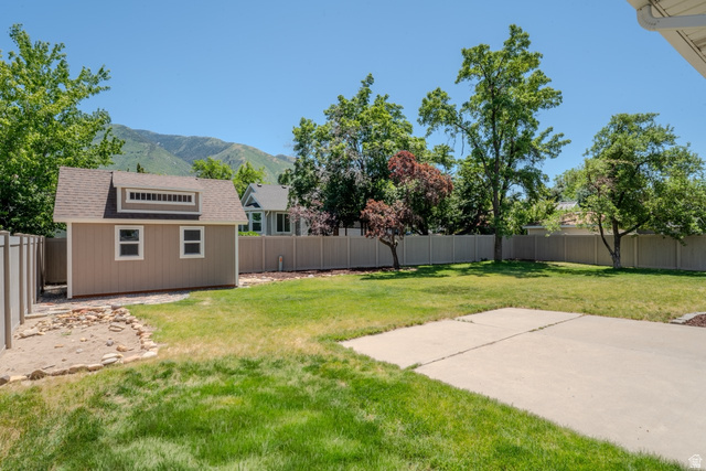 11957 Noelle Road Sandy, UT 84092 - Photo 37 of 38 Expansive backyard featuring a large concrete patio, a dedicated storage shed with multiple windows, and a full privacy fence