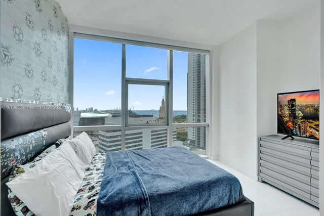 a bedroom with a bed and a flat tv screen on dresser
