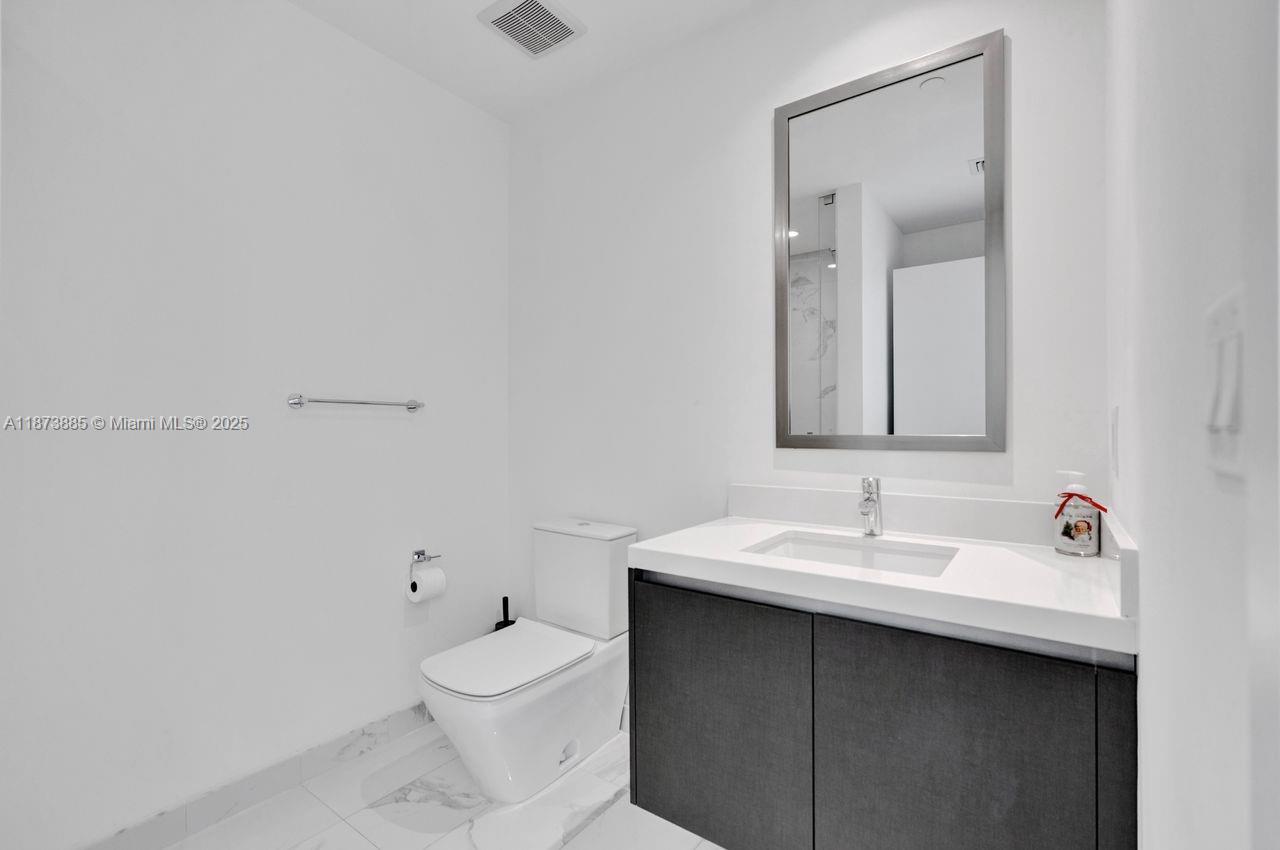 851 Northeast 1st Avenue, Unit 1411 Miami, FL 33132 - Photo 26 of 58 a bathroom with a sink a toilet and mirror