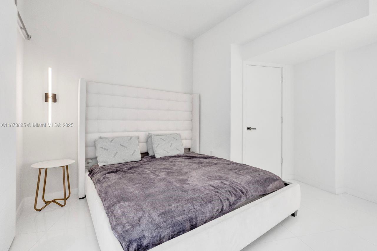 851 Northeast 1st Avenue, Unit 1411 Miami, FL 33132 - Photo 31 of 58 a large bed sitting in a room next to a lamp