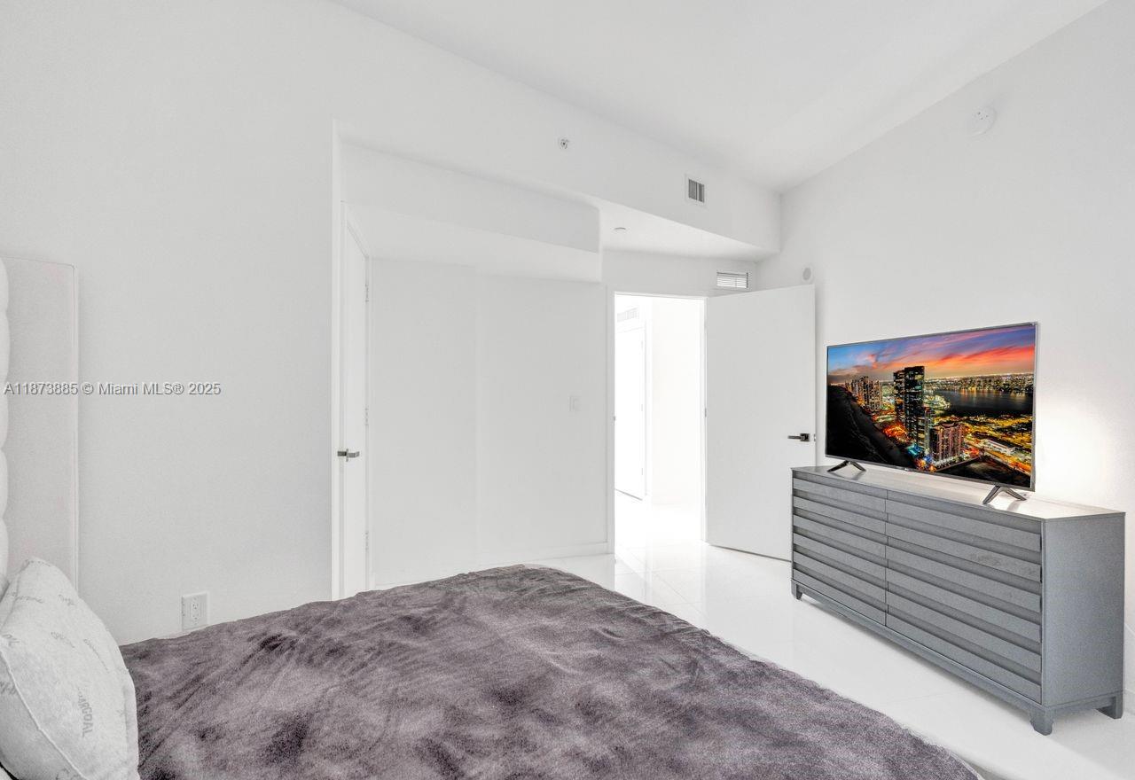 851 Northeast 1st Avenue, Unit 1411 Miami, FL 33132 - Photo 33 of 58 a bedroom with a bed and a flat screen tv