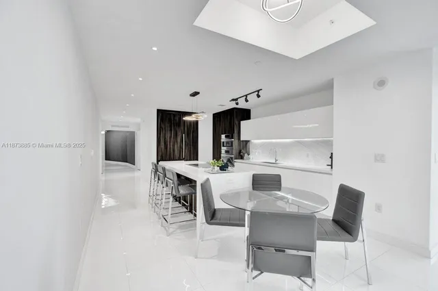a kitchen with a dining table chairs and refrigerator