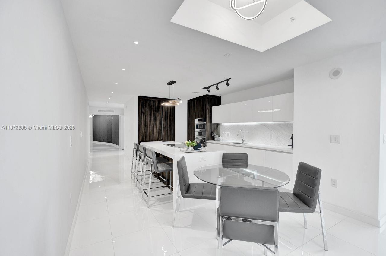 851 Northeast 1st Avenue, Unit 1411 Miami, FL 33132 - Photo 8 of 58 a kitchen with a dining table chairs and refrigerator