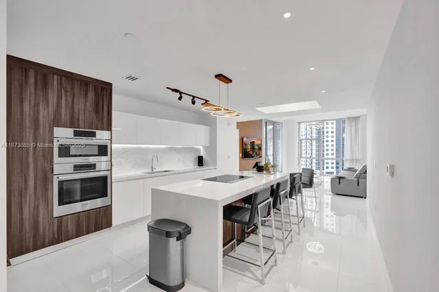 a open kitchen with stainless steel appliances kitchen island granite countertop a refrigerator oven a sink dishwasher and white cabinets with wooden floor