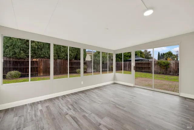 a view of an empty room with glass door and wooden floor