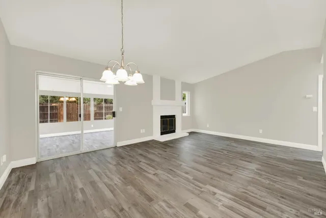 a view of a livingroom with a chandelier wooden floor and windows