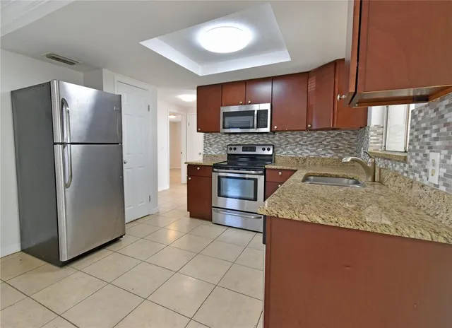 a kitchen with stainless steel appliances granite countertop a refrigerator a sink a stove a microwave and island