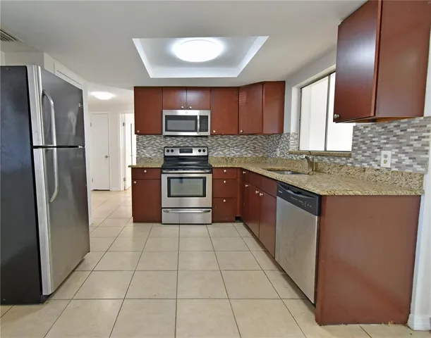 a kitchen with stainless steel appliances granite countertop a stove a sink and a refrigerator