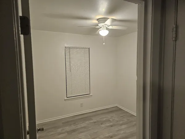 an empty room with windows and fan