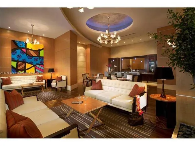 a living room with furniture kitchen view and a chandelier