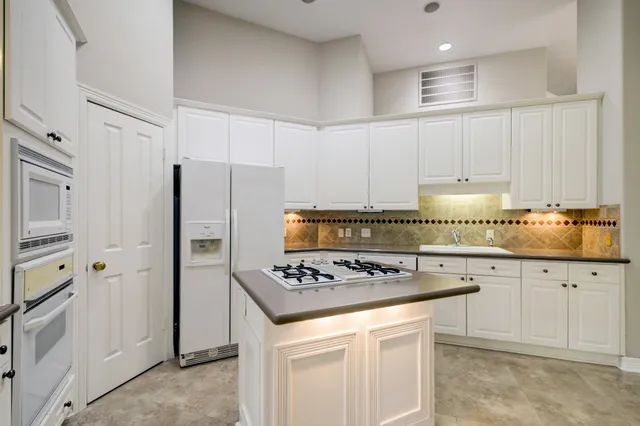 a kitchen with granite countertop a sink stove and refrigerator