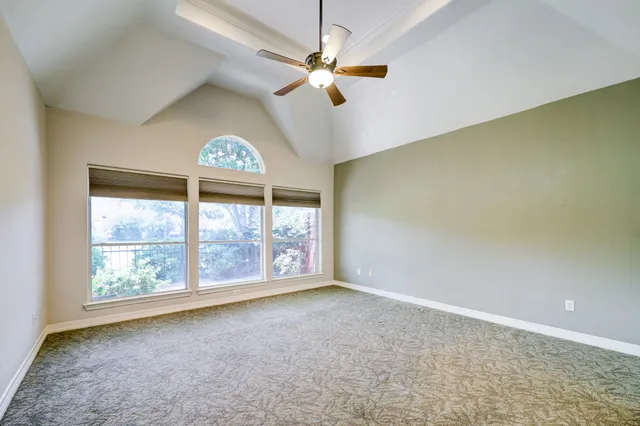 an empty room with windows and fan