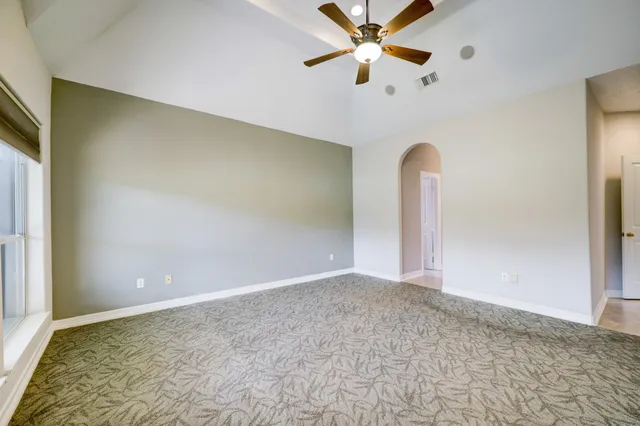 a view of an empty room with a chandelier fan