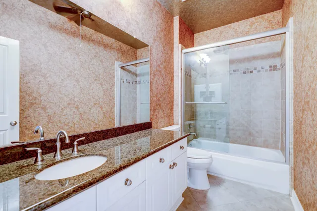 a bathroom with a granite countertop tub sink toilet and mirror