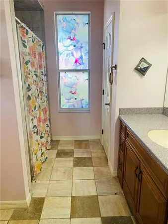 a bathroom with a granite countertop sink a mirror and shower