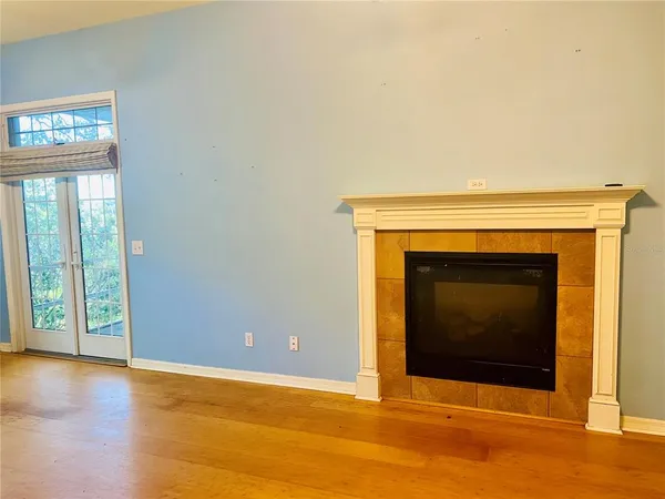 a view of an empty room with wooden floor and a fireplace