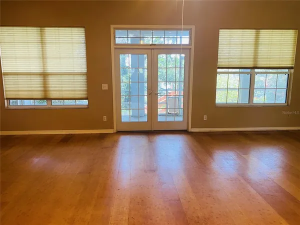 an empty room with wooden floor and windows