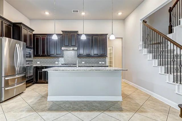 a view of kitchen with granite countertop cabinets and refrigerator