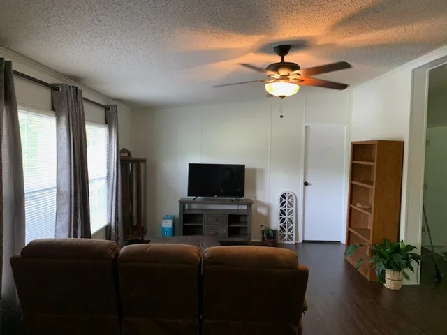 a living room with furniture a ceiling fan and a flat screen tv
