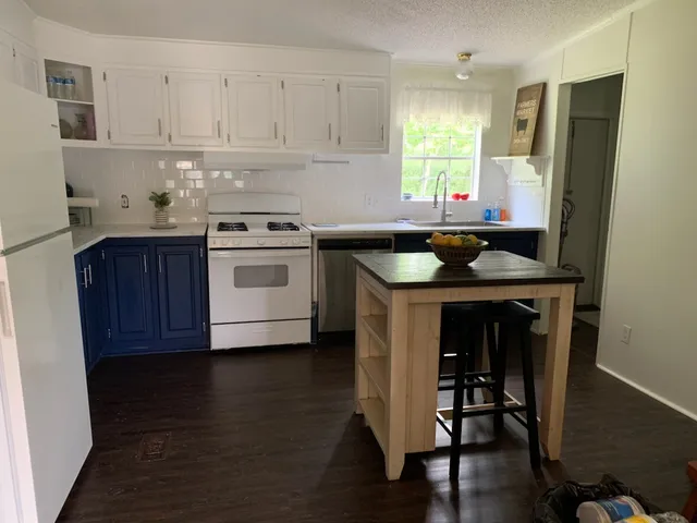 a kitchen with a stove a sink wooden floor and a refrigerator