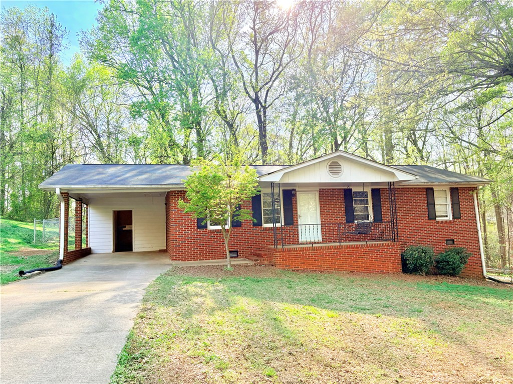 This classic brick residence offers a welcoming facade with a convenient carport and lush surroundings.