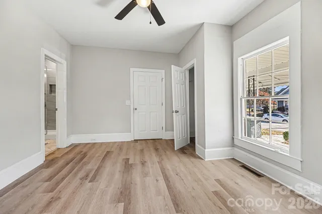 an empty room with windows and fan