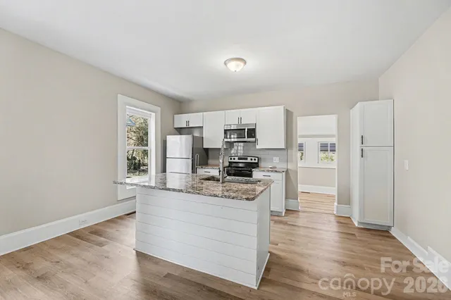 a kitchen with granite countertop a sink stove and refrigerator