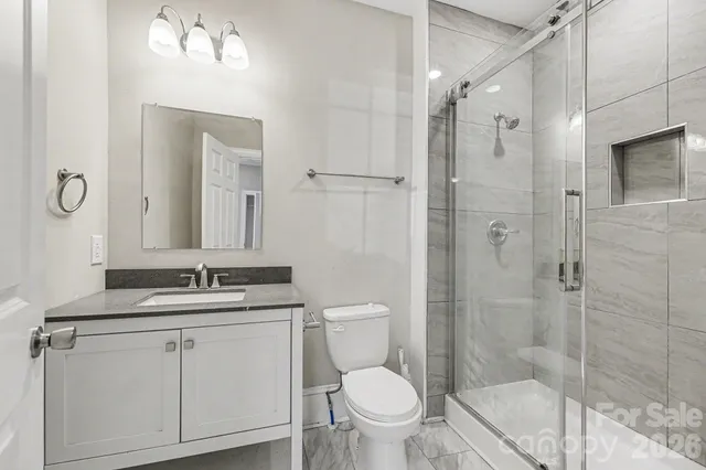 a bathroom with a granite countertop sink toilet a mirror a shower and vanity