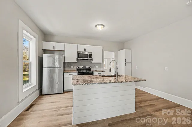 a kitchen with stainless steel appliances granite countertop a refrigerator a stove and a sink