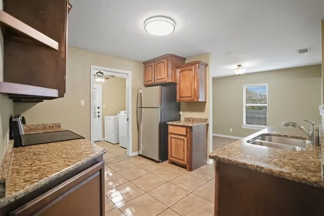 a kitchen with granite countertop a sink stove and refrigerator