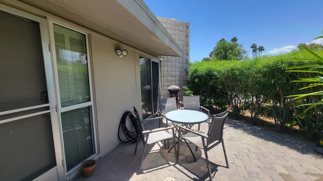 a patio with table and chairs and potted plants